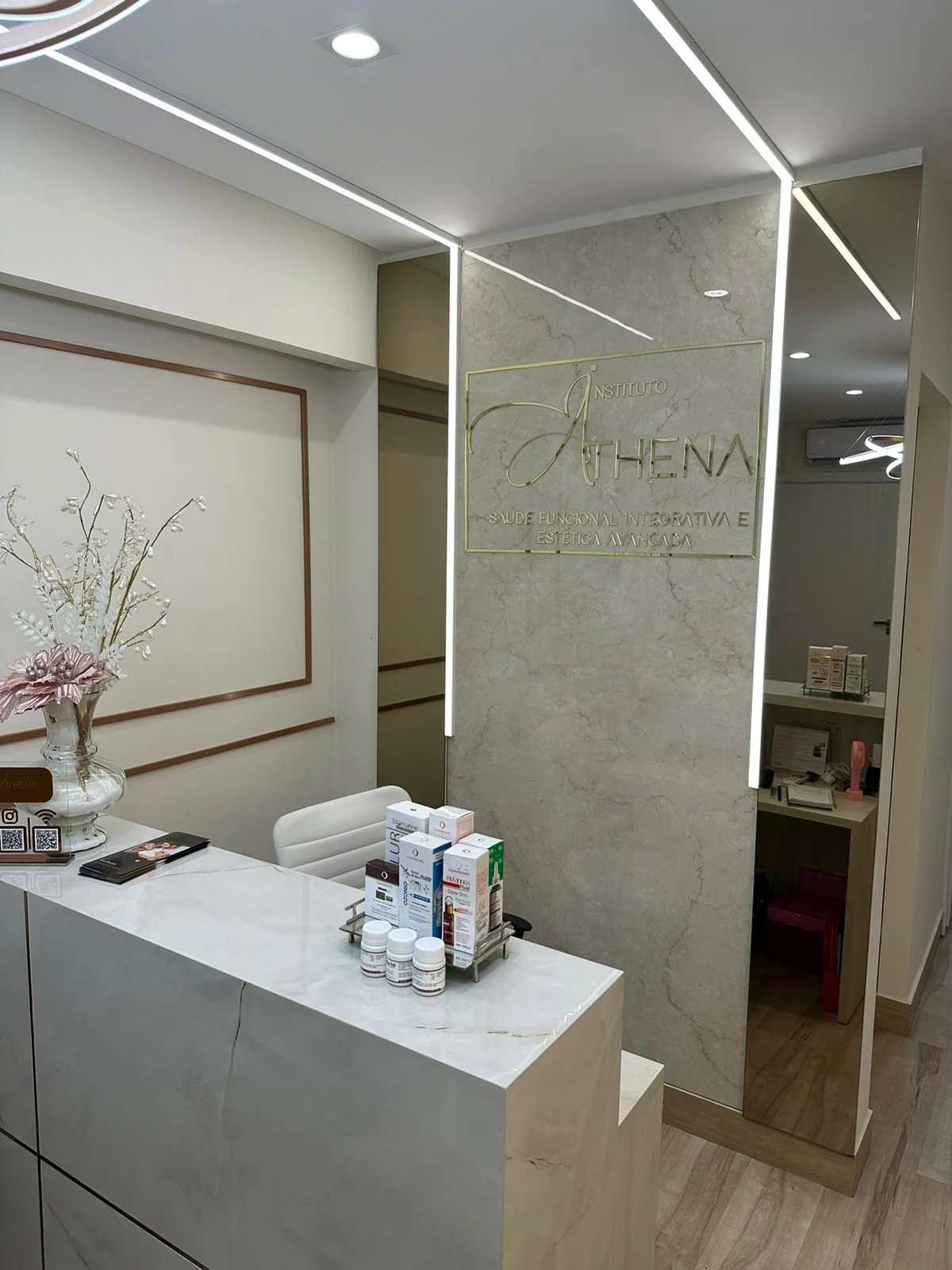Interior do Instituto Athena, com bancada, flores e a marca na parede